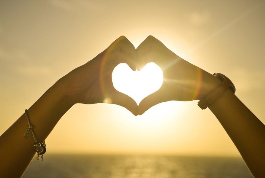 two women's hands making a love heart that symbolises lgbt dating in australia 