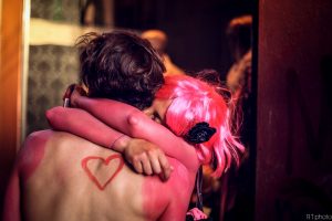 A pink love heart drawn on a guys back while a girl hugs him thinking about the GCN Pride Guide 2016