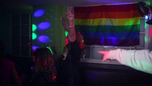 A girl dancing in the Only Gay Bar In The Village with a rainbow flag