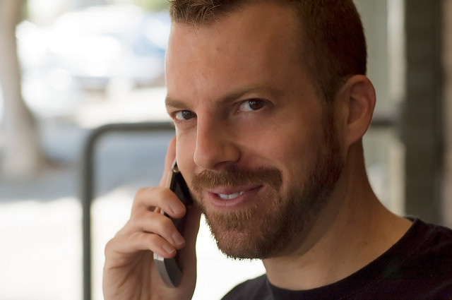 a man on the phone with a cheeky grin as he's in a long distance relationship