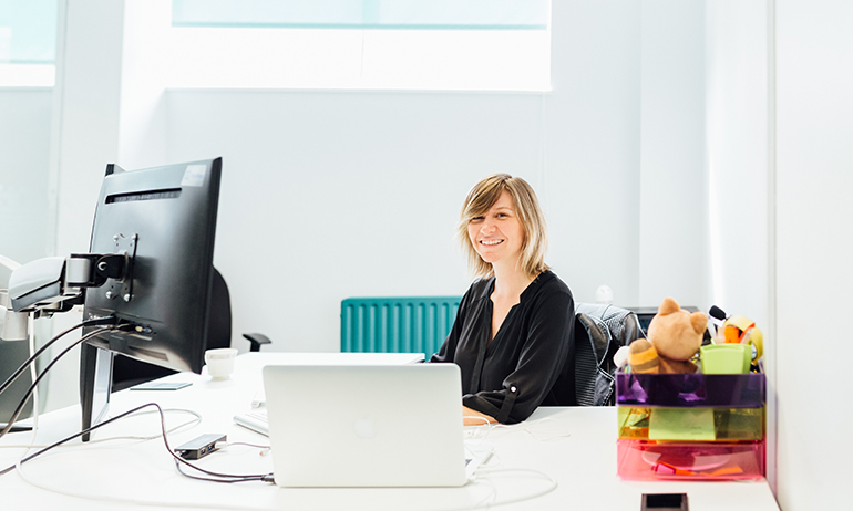 Kerrie Power sitting at a desk with computers in front of her is one of the LGBT people in Real Irish Jobs