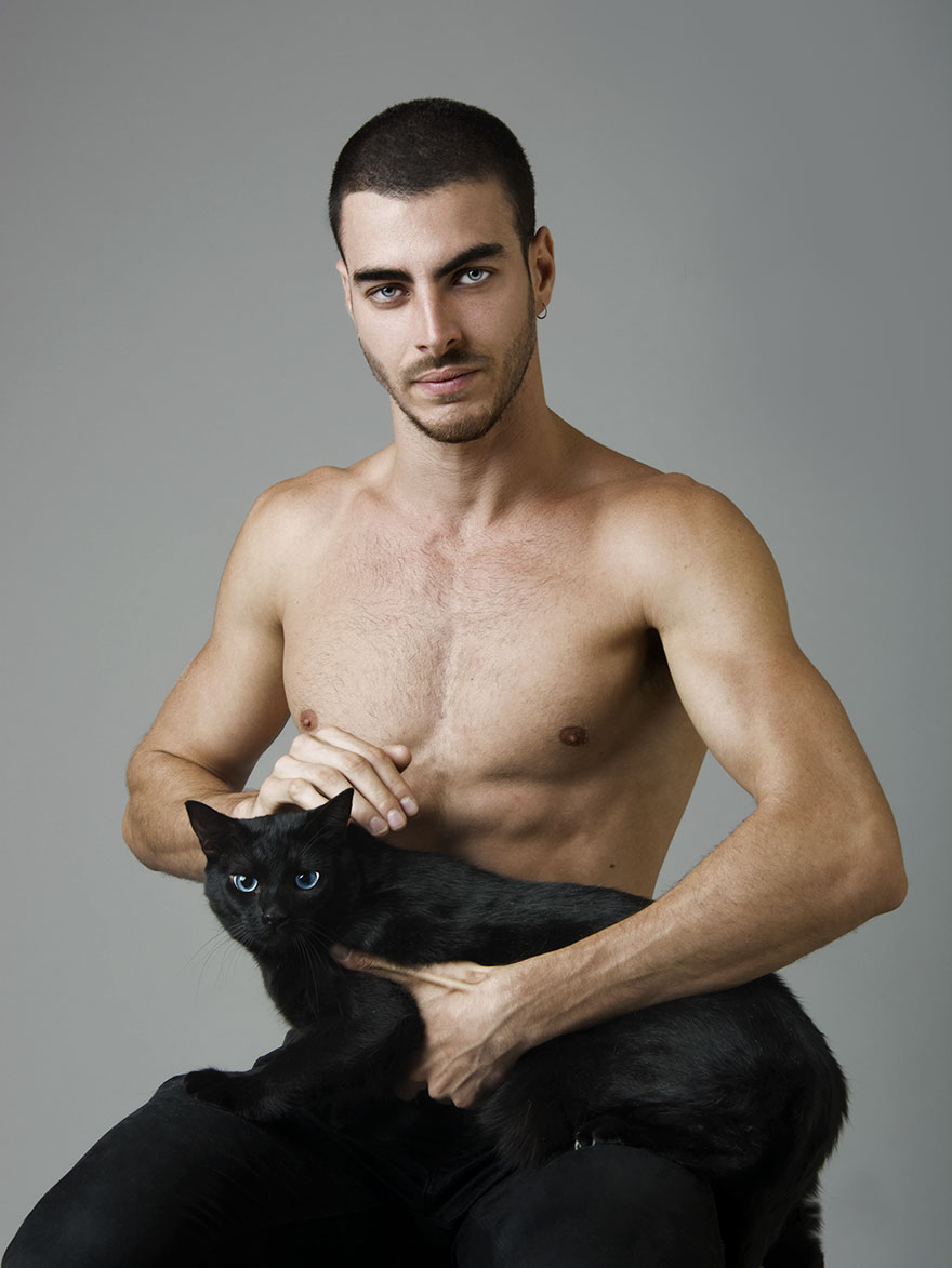 A topless man petting a black cat