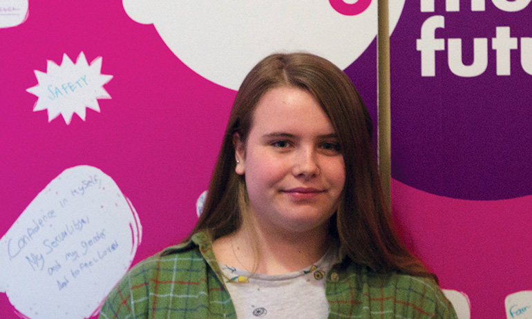 Katie standing in front of the belong to sign, who is one of the young Irish LGBT interviewed for GCN's 2016 Youth Issue