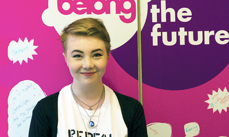 Remus standing in front of the belong to sign, who is one of the young Irish LGBT interviewed for GCN's 2016 Youth Issue