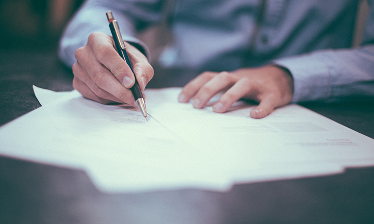 A man writing on paper to symbolise the legalities of buying PrEP in GCN's guide on where tof buy PrEP online