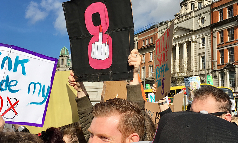 A Strike 4 Repeal sign with a middle finger over a pink 8