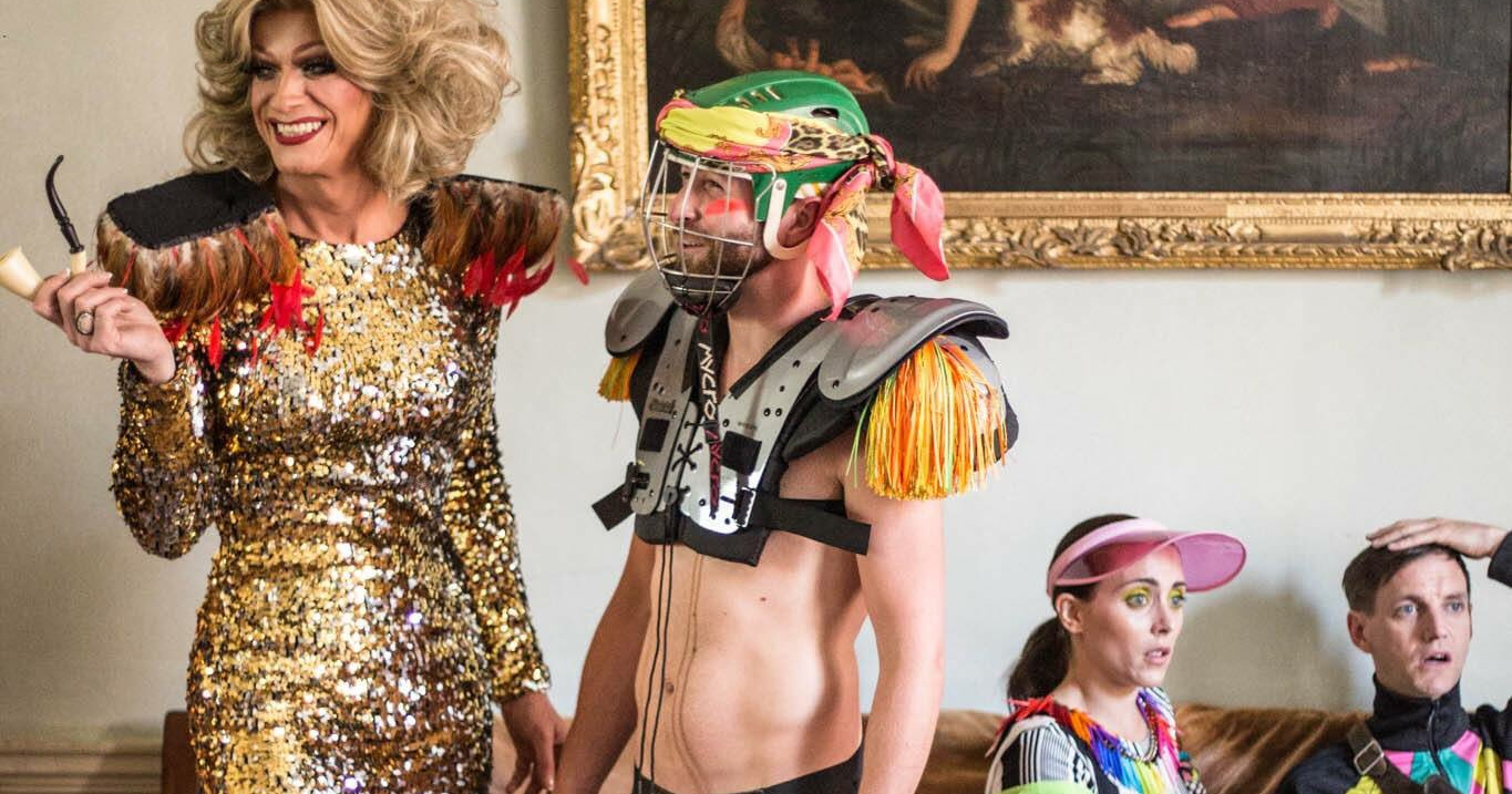 Panti, Adam Matthews laughing while standing, two other cast members are sitting in the background