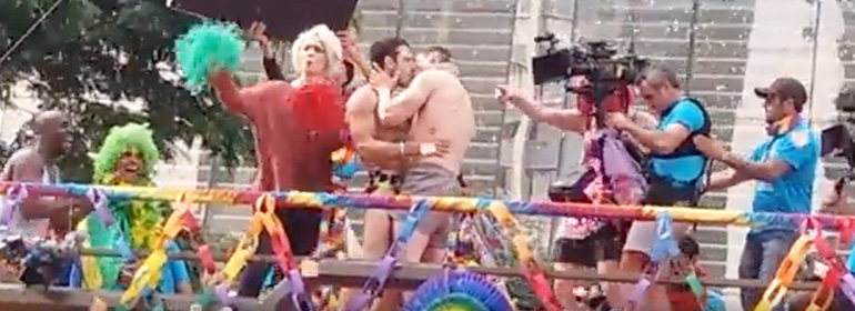 The Sense8 cast at pride with Lito and Will kissing on a pride float and Riley standing beside them