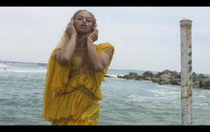 Trans Beyoncé Impersonator in a yellow dress at the sea