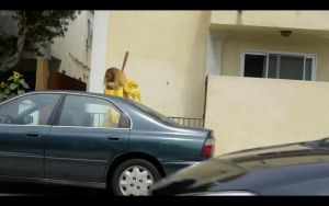 Trans Beyoncé Impersonator smashing a car window with a baseball bat