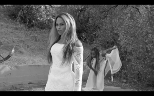 Trans Beyoncé Impersonator in a white lace dress with a dancer giving fierce side-eye