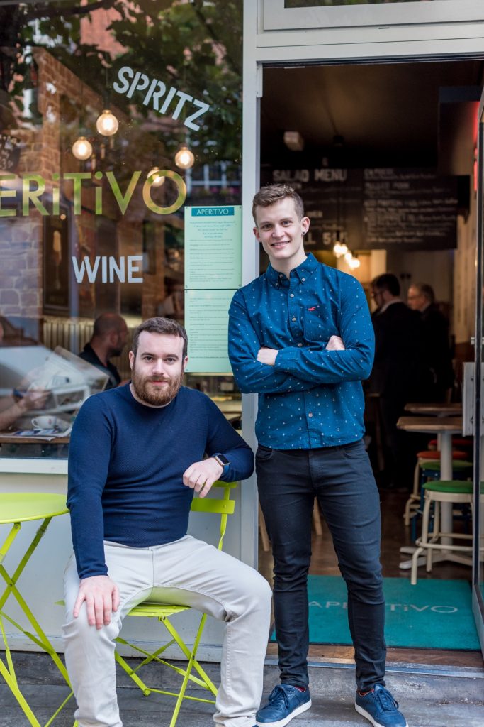 Renan and Paul Keville sitting and standing outside Aperitivo