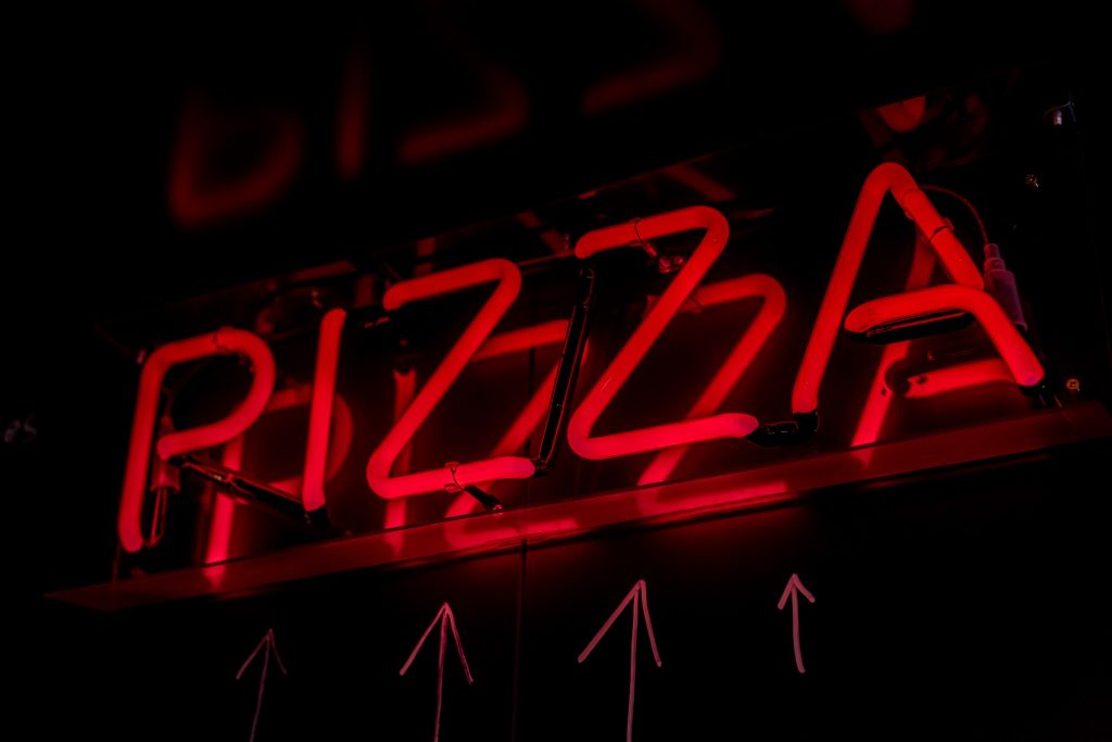 Glowing red pizza sign in Aperitif