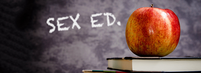 Sex ed written on a blackboard with a red apple in front of it, just as Irish sex education is out of touch according to a new study.