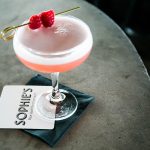 A pink cocktail with raspberry on a card saying sophie's at sophie's restaurant at the dean hotel for the November 2016 Amuse Bouche