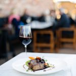 A piece of meat and glass of red wine at sophie's restaurant at the dean hotel for the November 2016 Amuse Bouche