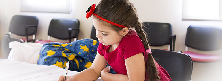 A girl sitting on her own with a pen and a red hairband, possibly as a result of homophobic bullying, which primary school principals are dismissing as not important enough to tell the school board