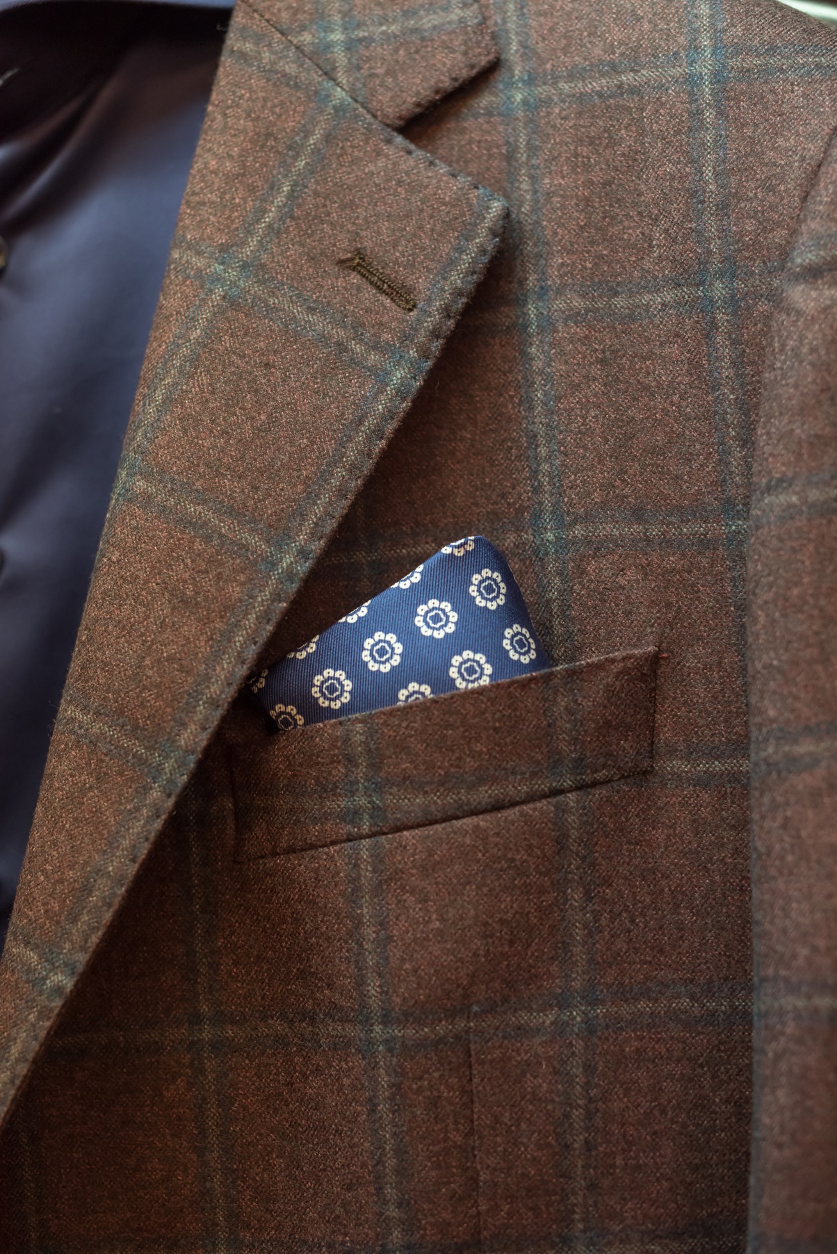 A brown suit with a blue pocket square at a Louis Copeland store