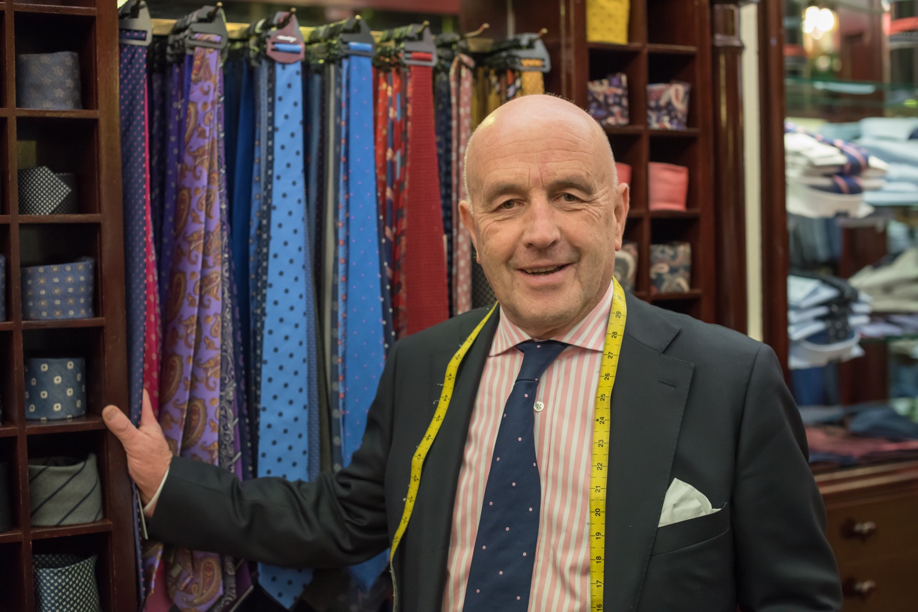 Louis Copeland standing with a tailoring measuring tape around his neck at a Louis Copeland store