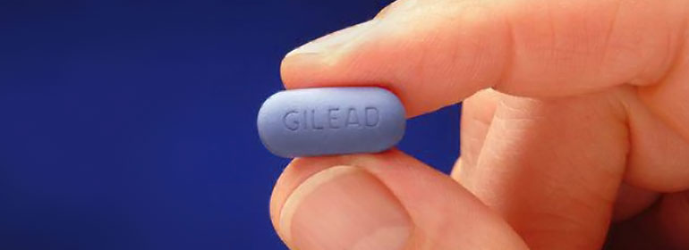 A truvada blue pill with gilead written on it held up by a hand, to symbolise the DISCOVER trial run by Gilead