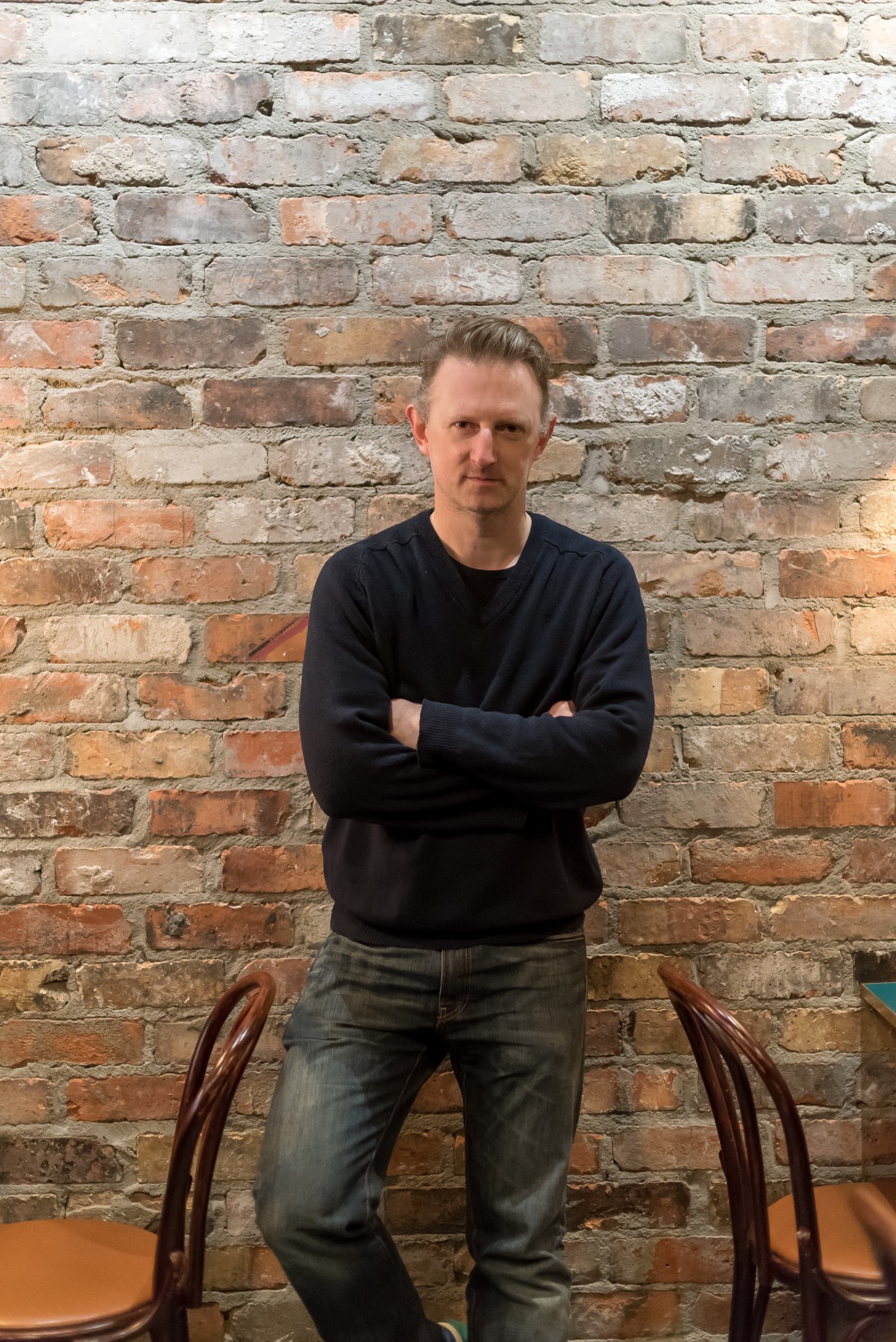 Temple Garner, the chef and owner of San Lorenzo's in front of a brick wall