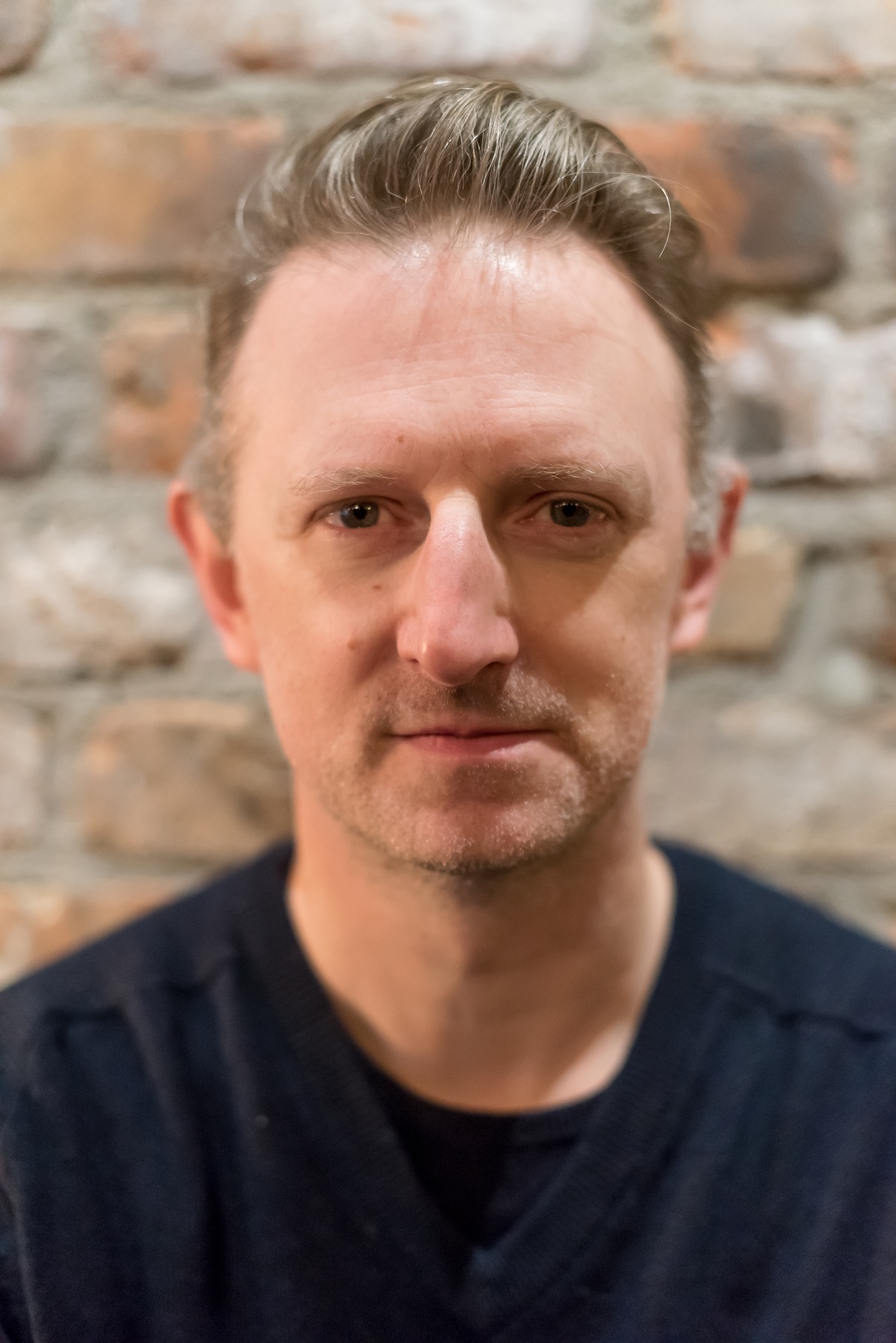 Temple Garner, the chef and owner of San Lorenzo's in front of a brick wall