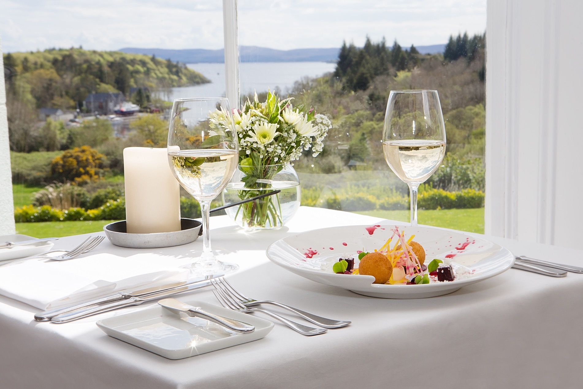 An interior shot of the lodge at ashford castle where if you book a wedding, you could win a luxury cruise to the value of e10000 with wine glasses and food on a white table with cutlery
