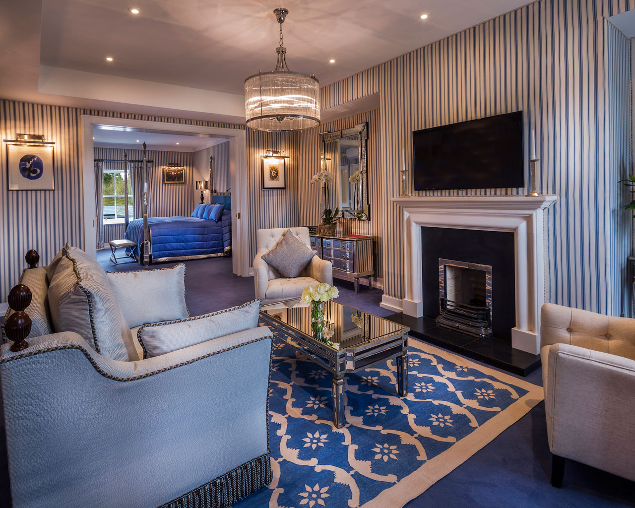 An interior shot of the lodge at ashford castle where if you book a wedding, you could win a luxury cruise to the value of e10000 with a blue bed, chairs and a fireplace
