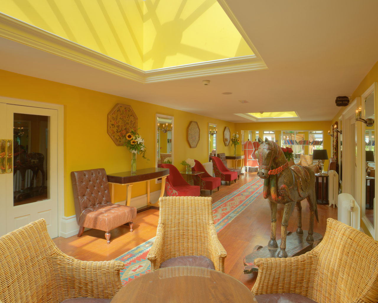 An interior shot of the lodge at ashford castle where if you book a wedding, you could win a luxury cruise to the value of e10000 with chairs and couches in a brightly lit yellow tinged room