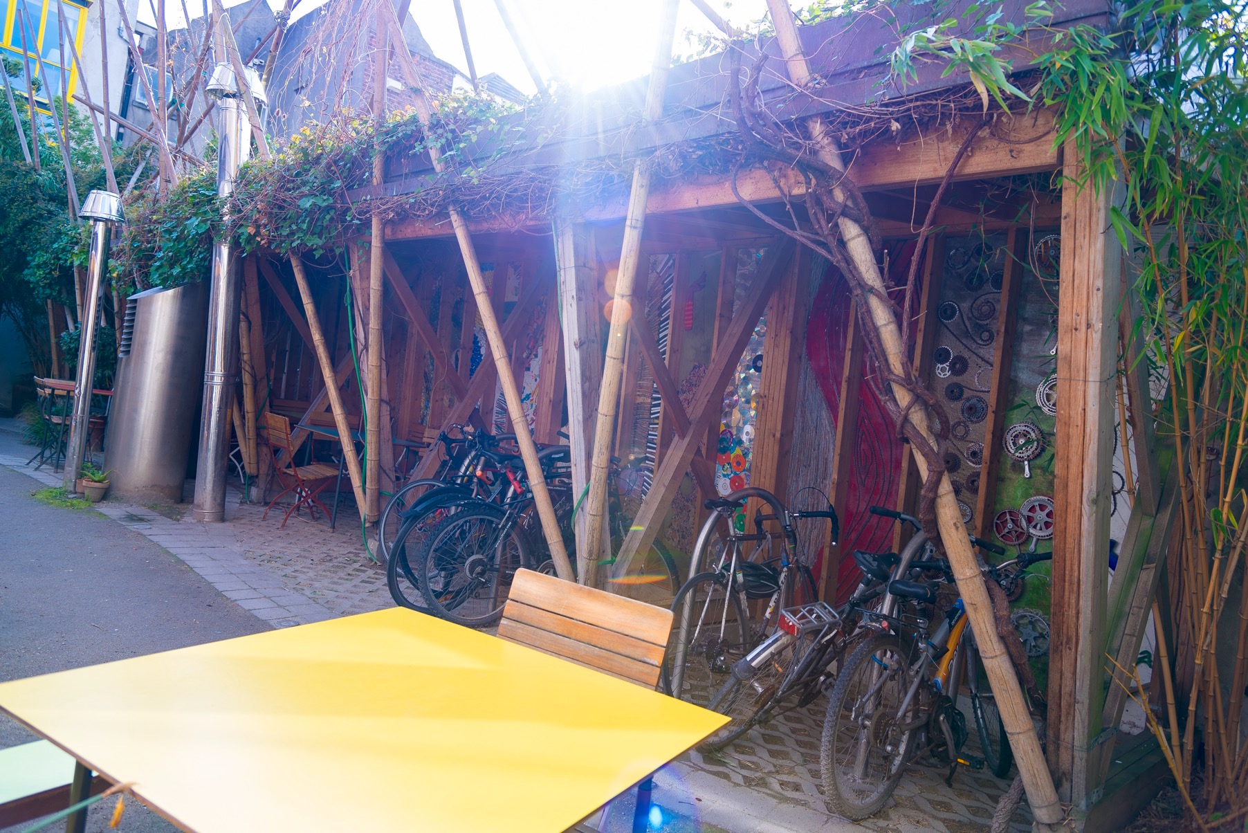 A yellow table, wooden chair and bike rack outside with the sun beaming down at the cake cafe and slice which are both owned by Ray O'Neill