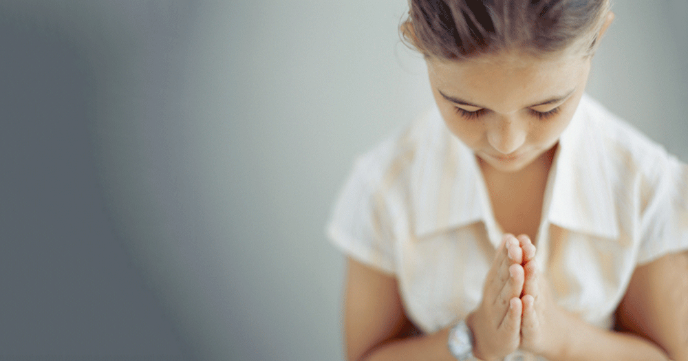 A child praying like children have to in the educating Ireland article about secular reform coming to Irish schools