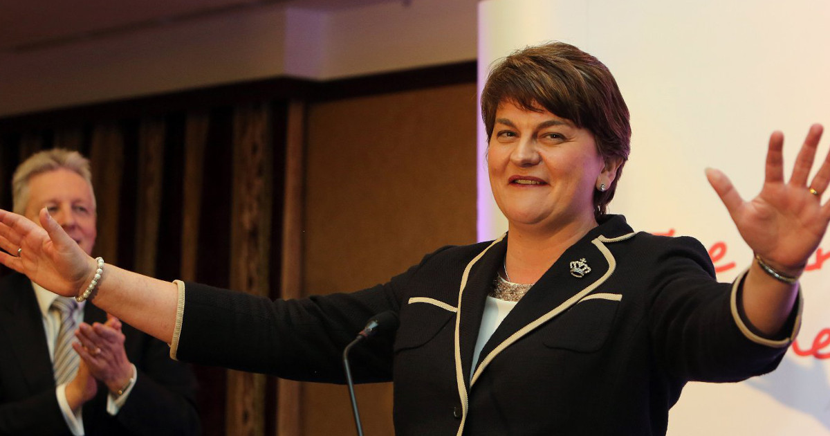 DUP leader arlene foster arms spread at a lectern as Peter Robinson looks on