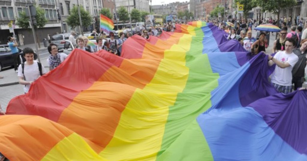 the rainbow flag is carried by an crowd of people down Dublin's O'Connell Street during Pride parade