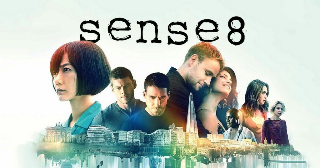 The stars of sense8 standing with the words Sense8 behind them