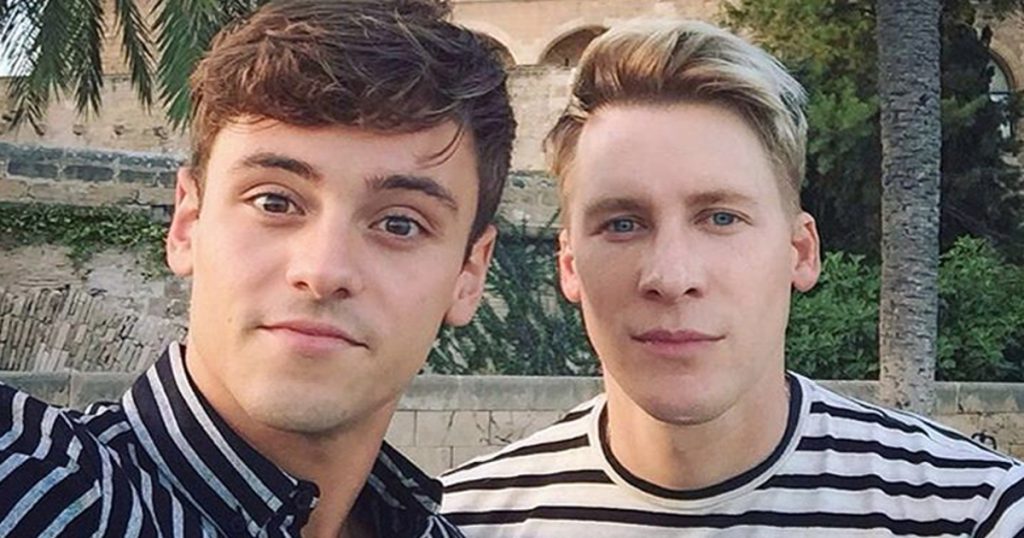 a young man and an older man look at a camera