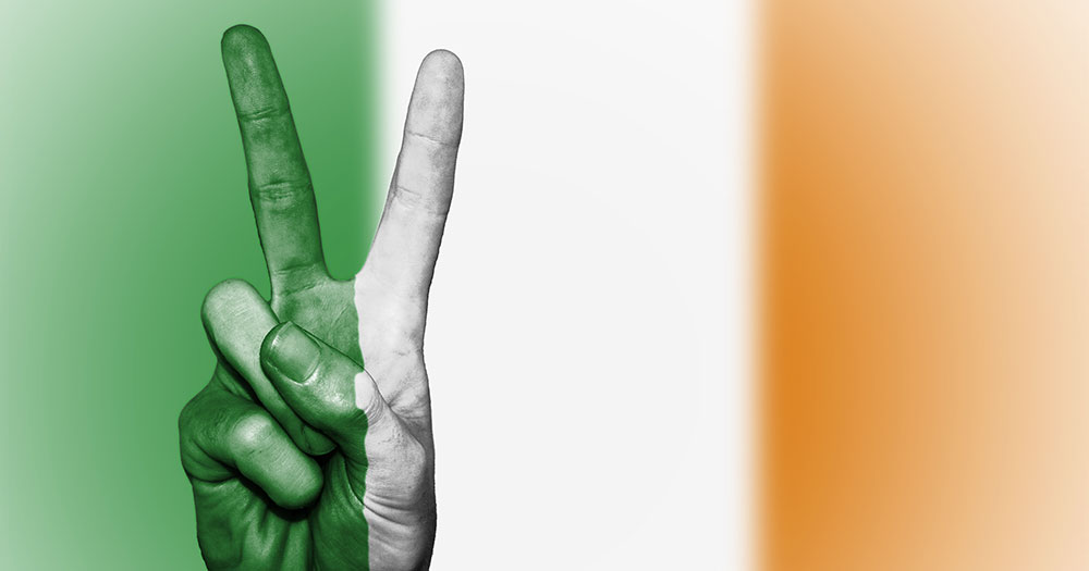 A person's hand doing the peace symbol in front of the irish flag for the dublin Human Rights Festival this weekend
