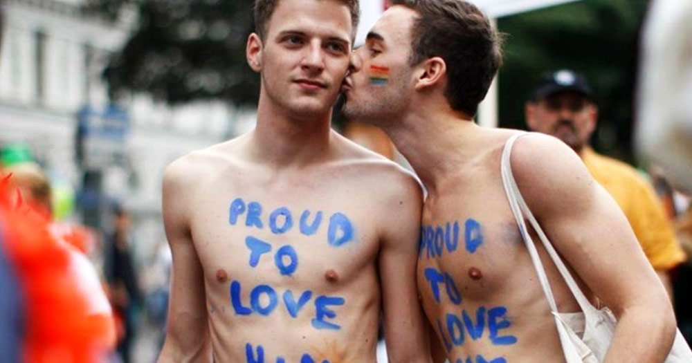 Two men at Austria Pride with "proud to love him" enscribed on their chests celebrate Marriage Equality