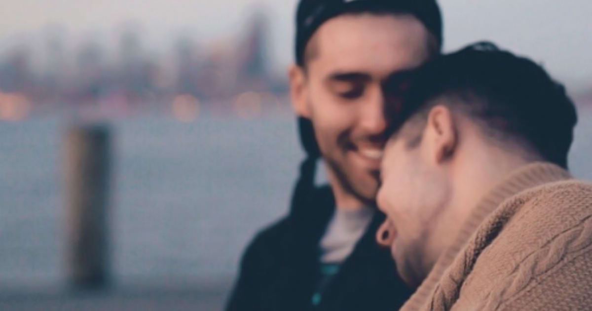 Two men on a bench snuggling