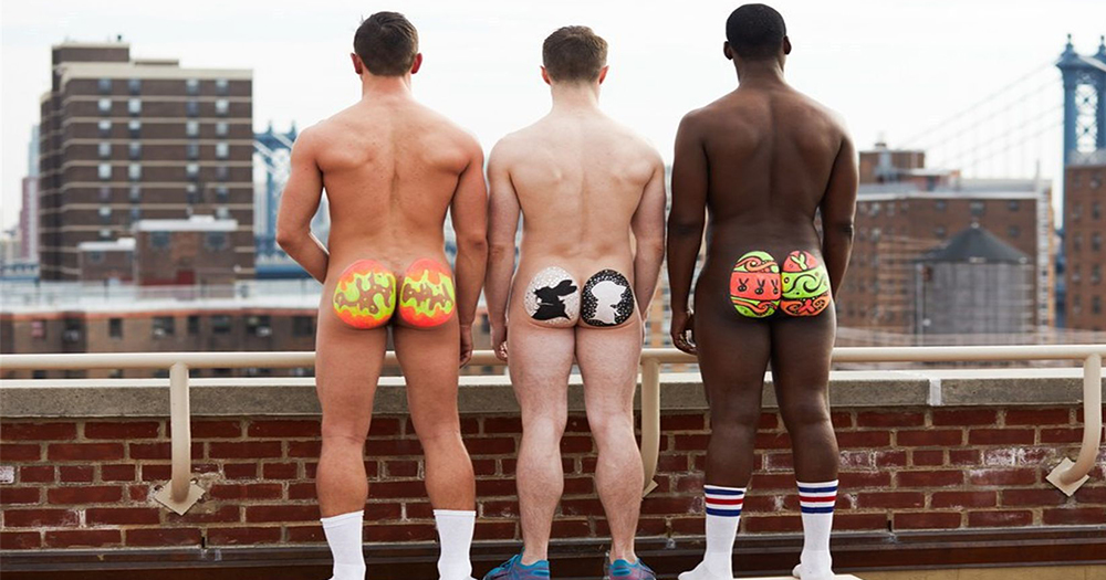 Three naked men with butts painted like Easter eggs standing on a rooftop in New York
