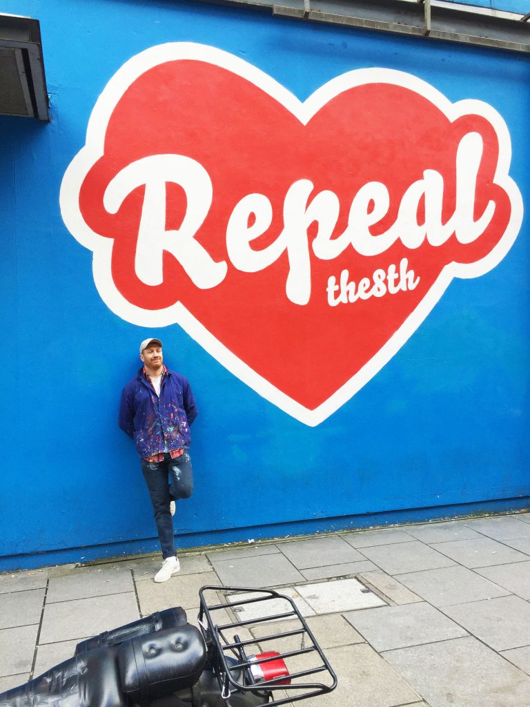 Artist Maser standing in front of the 'repeal the 8th' mural