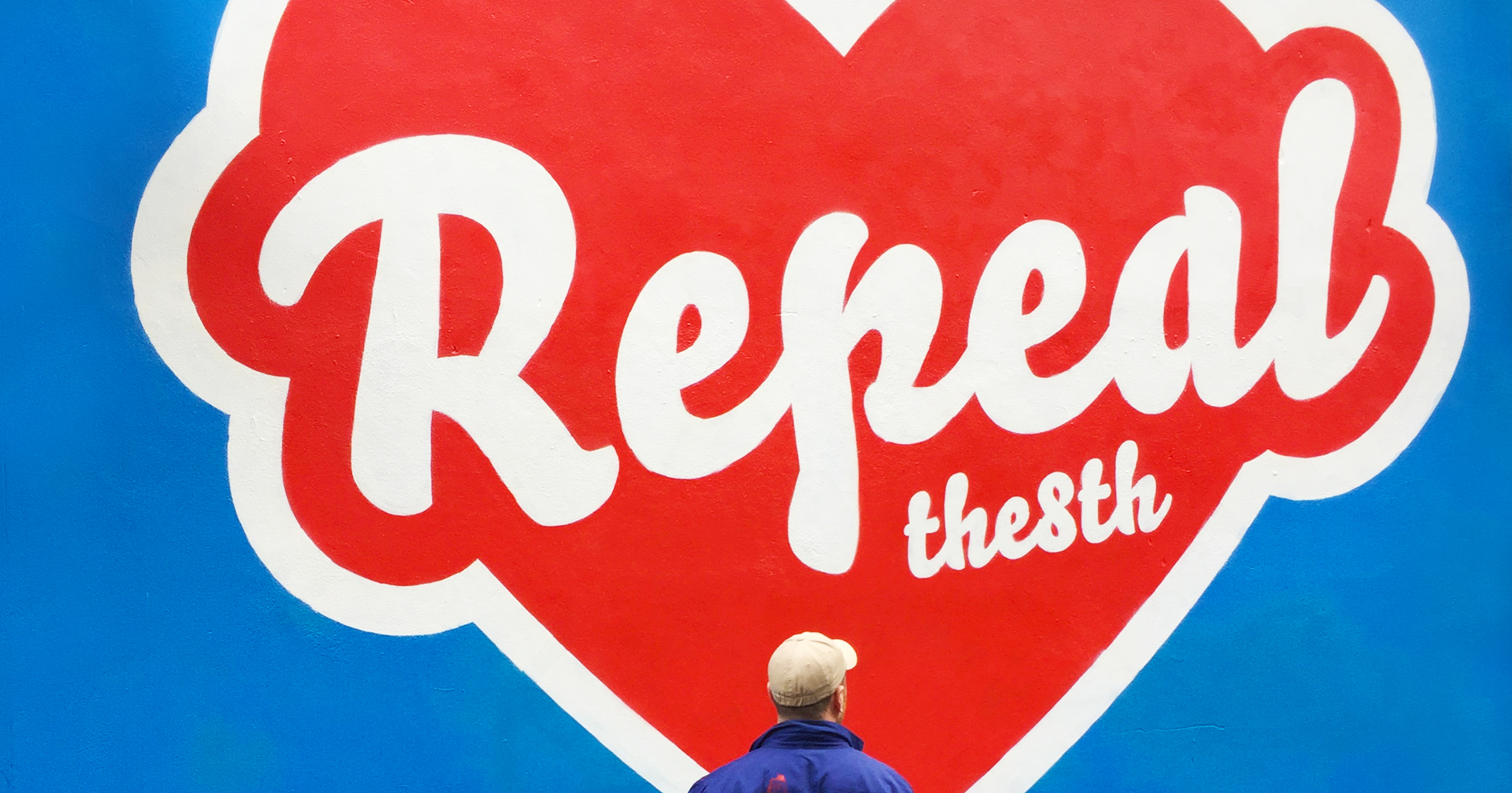 Artist Maser standing in front of the 'repeal the 8th' mural