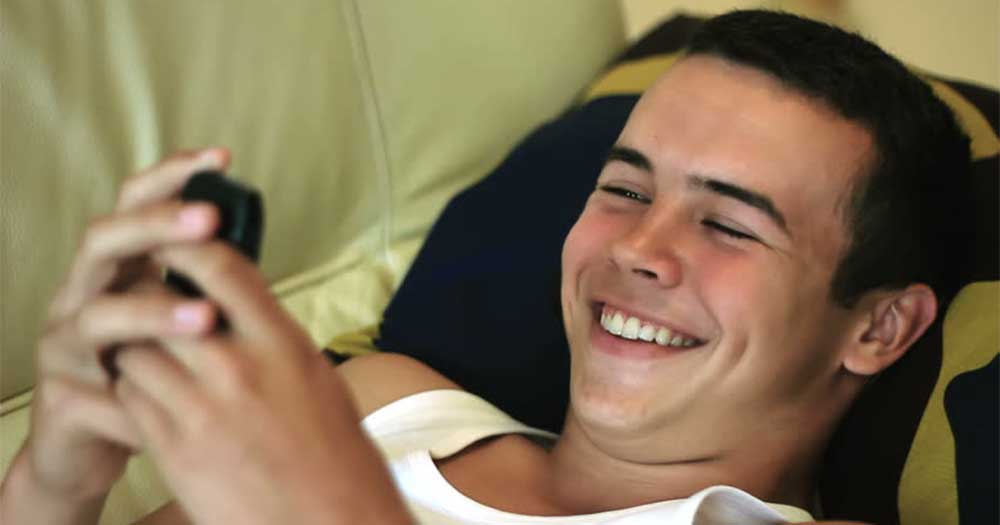 Underage teenage boy smiling at his phone
