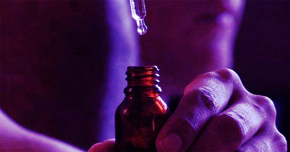 A closeup of someone taking a measure of the liquid drugs G from a bottle