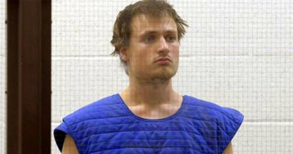 James Howell, the man arrested on his way to LA gay pride, in custody standing behind a mesh window wearing protective clothing, his hair tousled