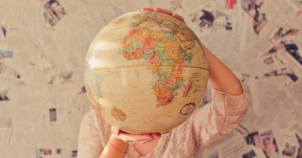 Queer on the map: person holds a globe