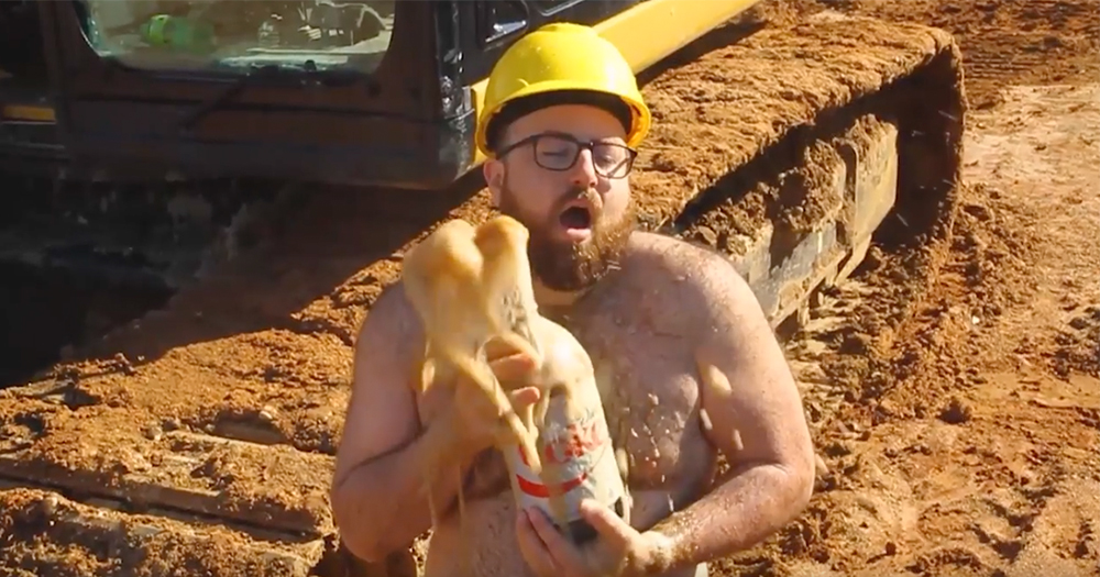 A topless bear in a hard hat poses sexily holding a large bottle of Diet Coke which has fizzed up all over him