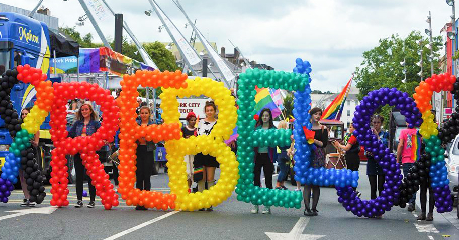 A group of people at Cork Pride holding rainbow coloured balloons which spell out REBELS