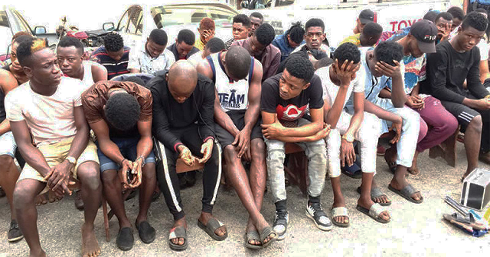 The group of men arrested in Nigeria for homosexual activity all lined up on a bench with their faces turned toward the ground