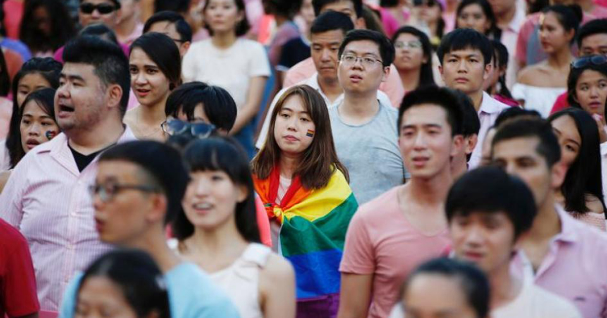 Girl wrapped in pride flag, surrounded by a crowd of people in Singapore