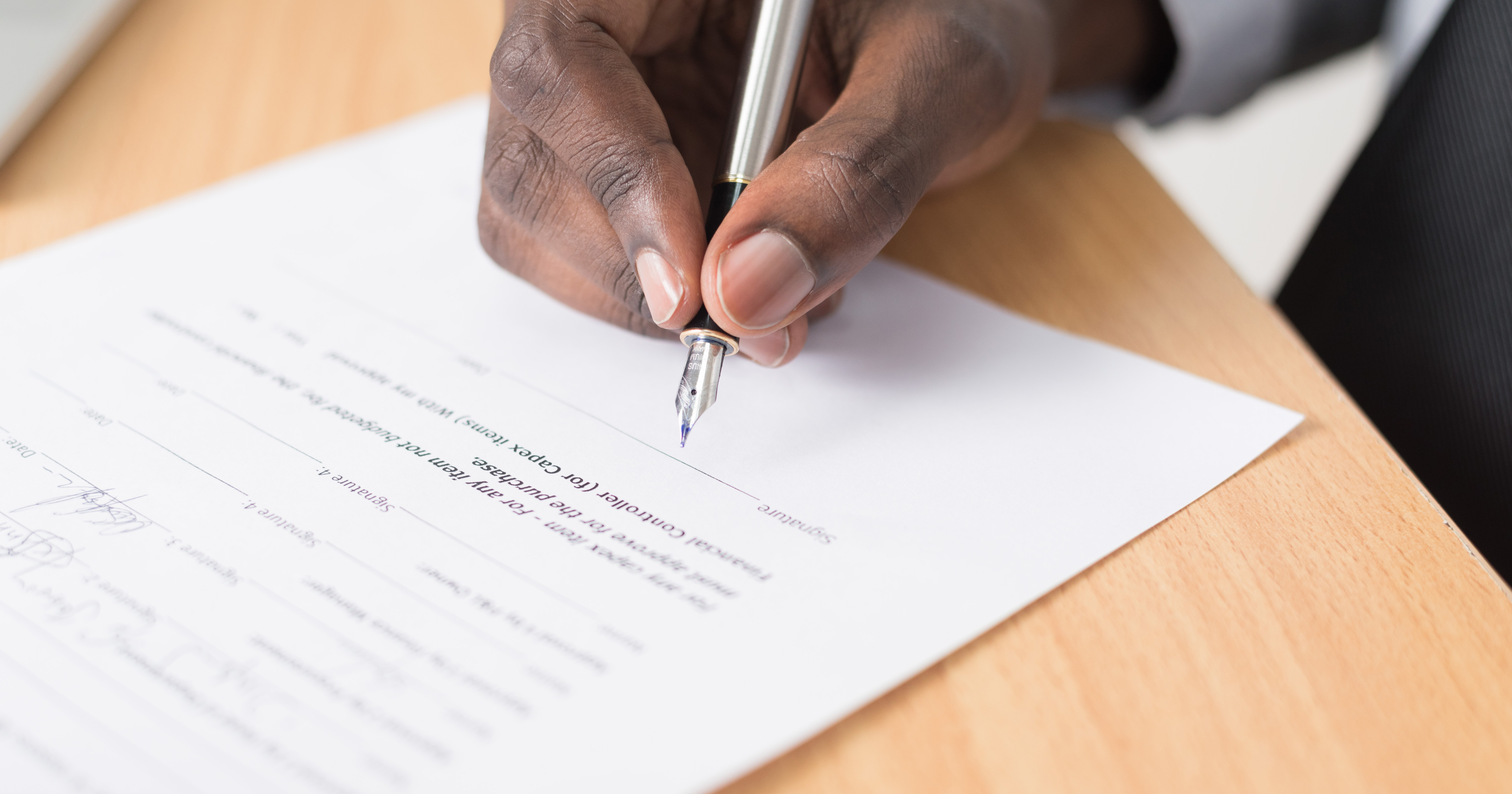 A person signing their will. CFI encourages people to leave charitable gifts in their wills.